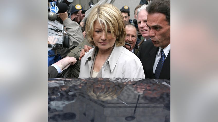 Martha Stewart in a white blouse and blazer stepping inside a car.