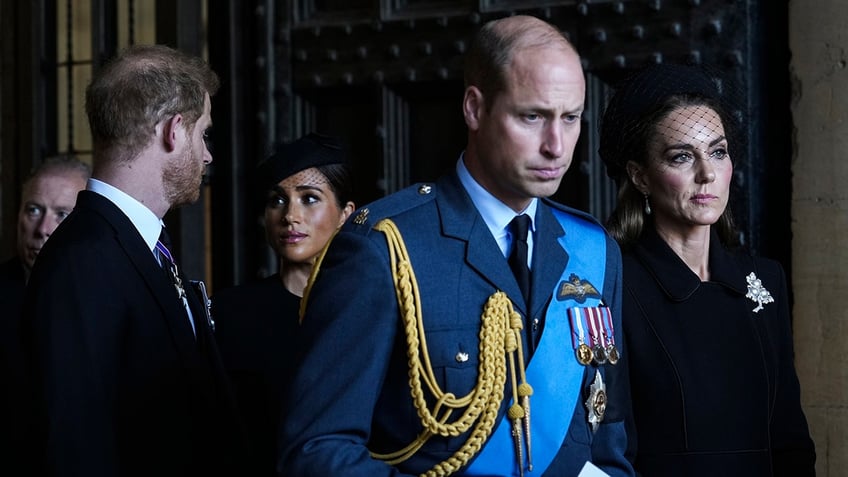 Prince William and Kate Middleton looking somber in front of Prince Harry and Meghan Markle.