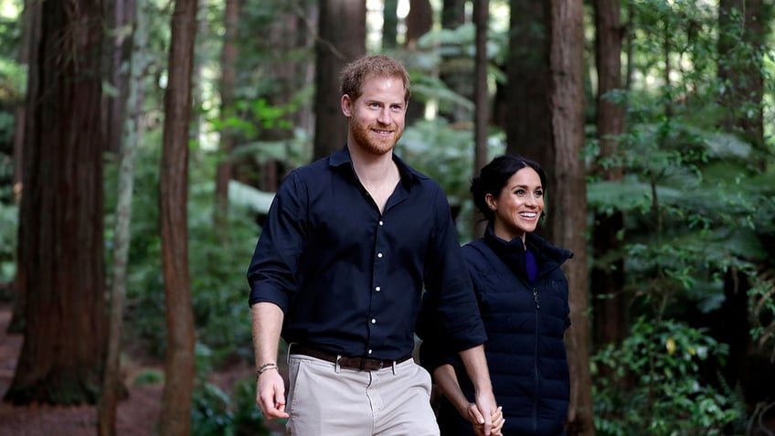 Prince Harry and Meghan Markle walking outdoors surrounded by tears.