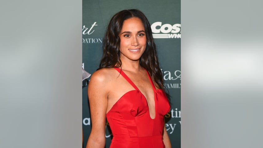 A close-up of Meghan Markle wearing a low-cut red dress.