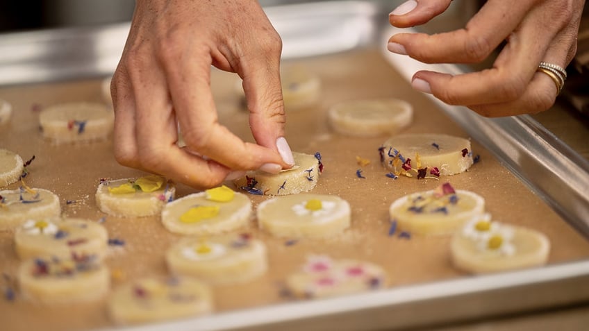 A close-up of Meghan Markle's hands working with flower sprinkles.