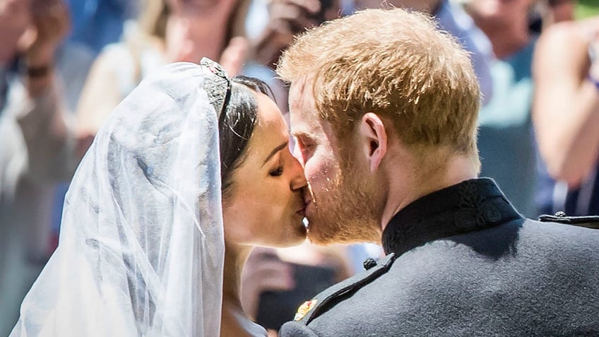 Meghan Markle and Prince Harry giving each other a kiss in their wedding attire.