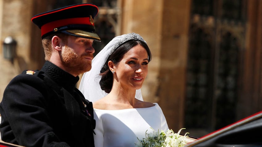 Prince Harry and Meghan Markle sitting in a royal carriage after their wedding.