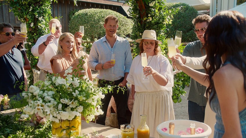 Meghan Markle having a toast with several friends outside in a garden with food