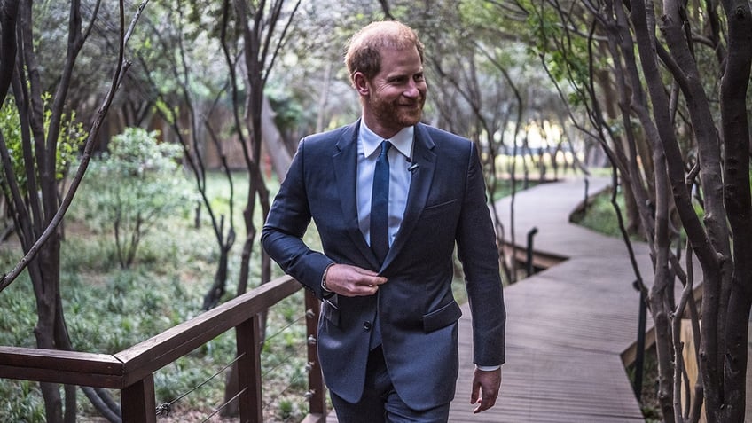 Prince Harry smiling in a blue suit.