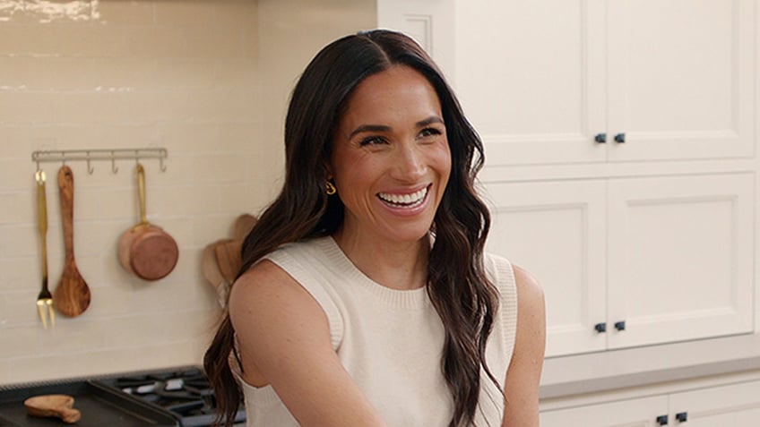 Meghan Markle laughs near the stove at home.