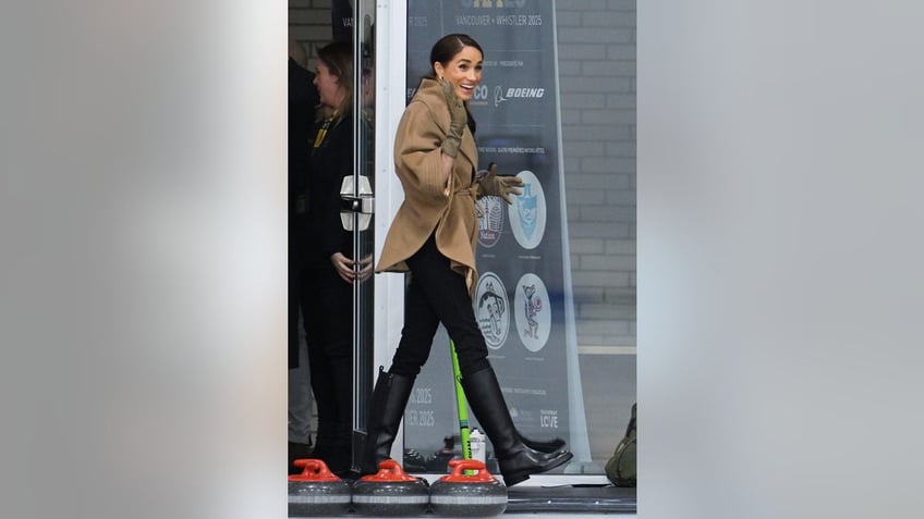 Meghan Markle wearing a beige coat and black slacks