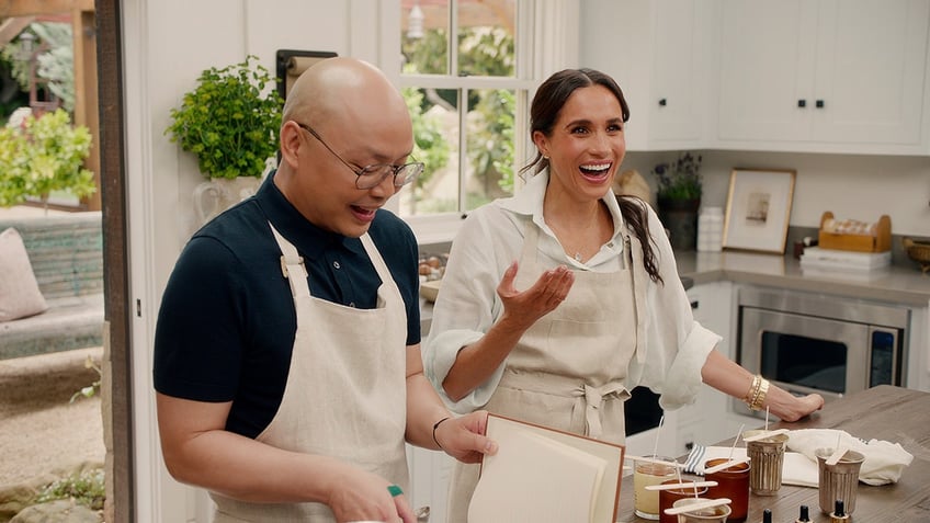 Meghan Markle smiling next to her friend Daniel Martin as they're in a kitchen.