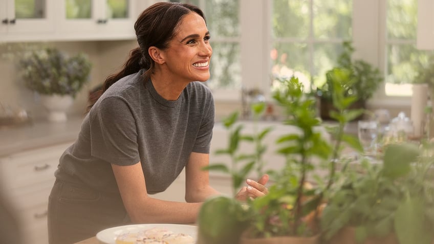 Meghan Markle smiling with a grey shirt.