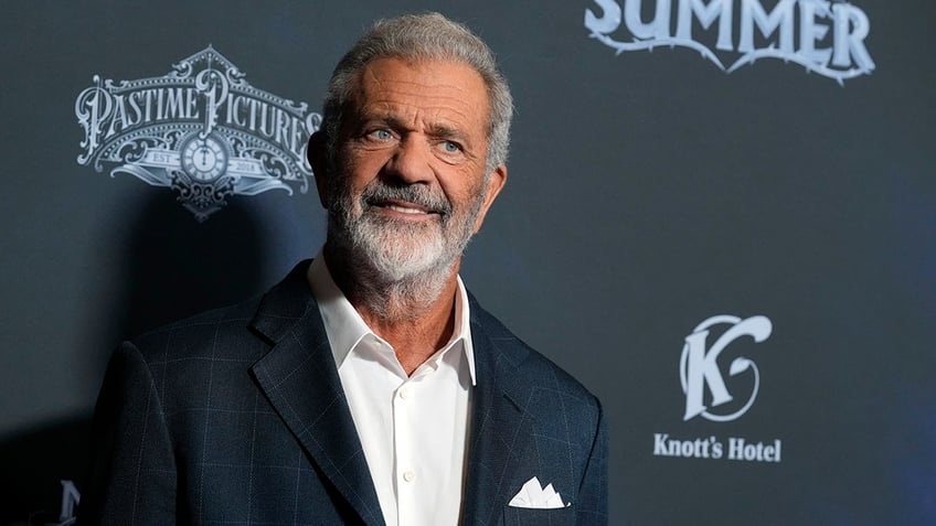 Actor Mel Gibson smiles on the red carpet wearing a blue suit