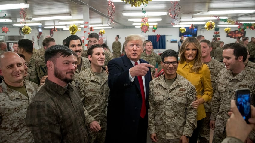 President Donald Trump and first lady Melania Trump pose for a photograph as they visit members of the military at a dining hall at Al Asad Air Base, Iraq, Wednesday, Dec. 26, 2018. (AP Photo/Andrew Harnik)