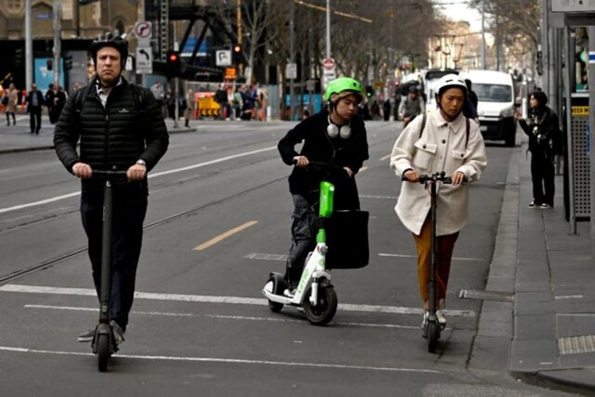 People ride e-scooters in Melbourne's central business district on August 14