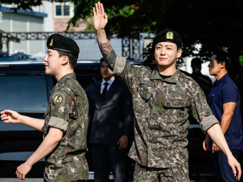 Jungkook (R) and Jimin (L) of K-pop supergroup BTS waves as they depart from an outdoor sp