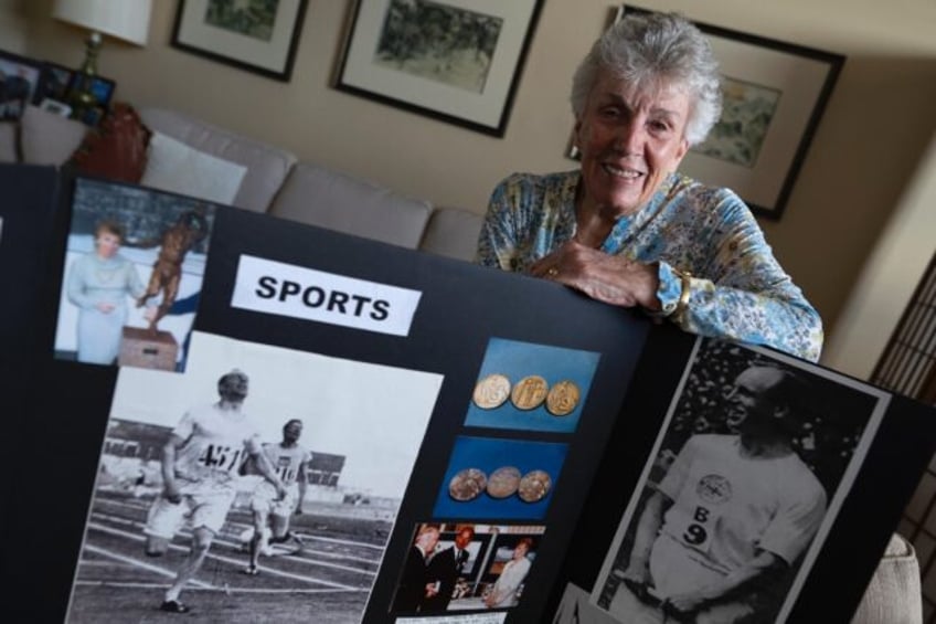 Patricia Russell, the eldest daughter of Eric Liddell, poses with photographs of her fathe