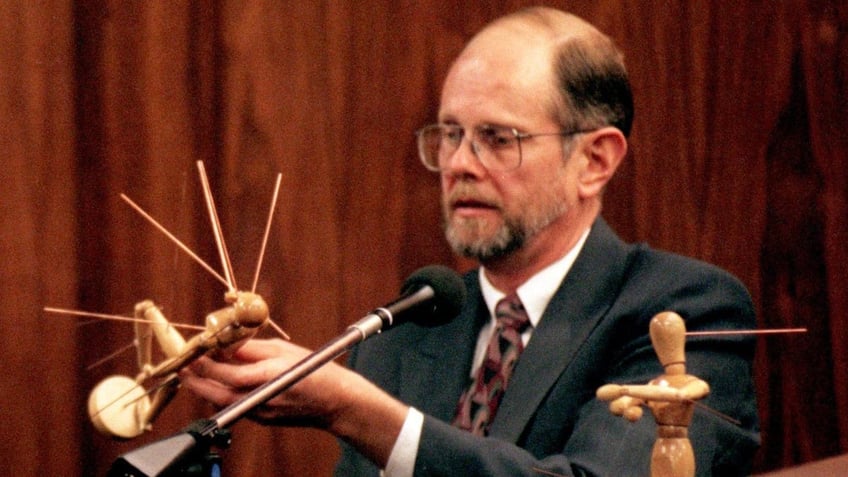 Dr. Robert Lawrence of Stockton, California, holds mannequin illustrating bullet wounds to Kitty Menendez during the Menendez brothers' murder trial in 1995