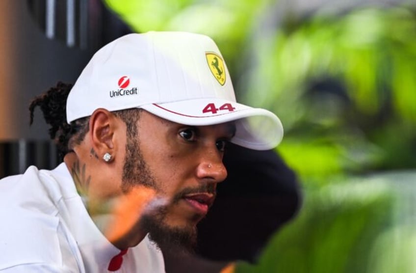 Ferrari's British driver Lewis Hamilton looks on at the F1 team village ahead of the 2025