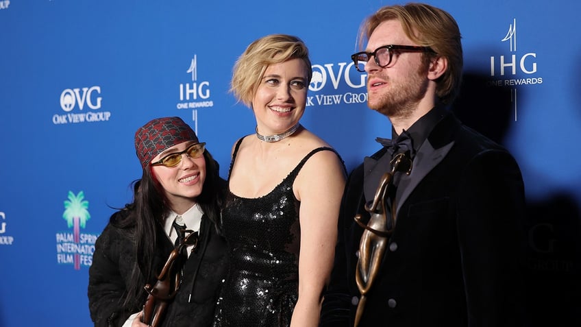 Billie Eilish looks lovingly at brother Finneas standing on the carpet in between "Barbie" director Greta Gerwig