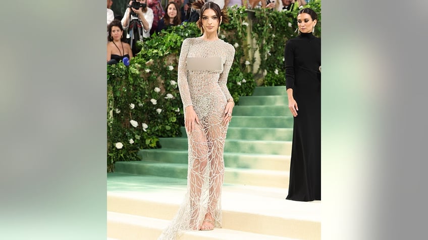 Emily Ratakowski at the Met Gala 2024 red carpet in a sheer crystal Versace dress.