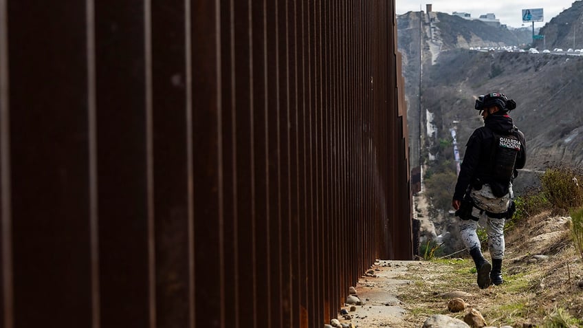 A National Guard officer monitors the border wall between Mexico and the US