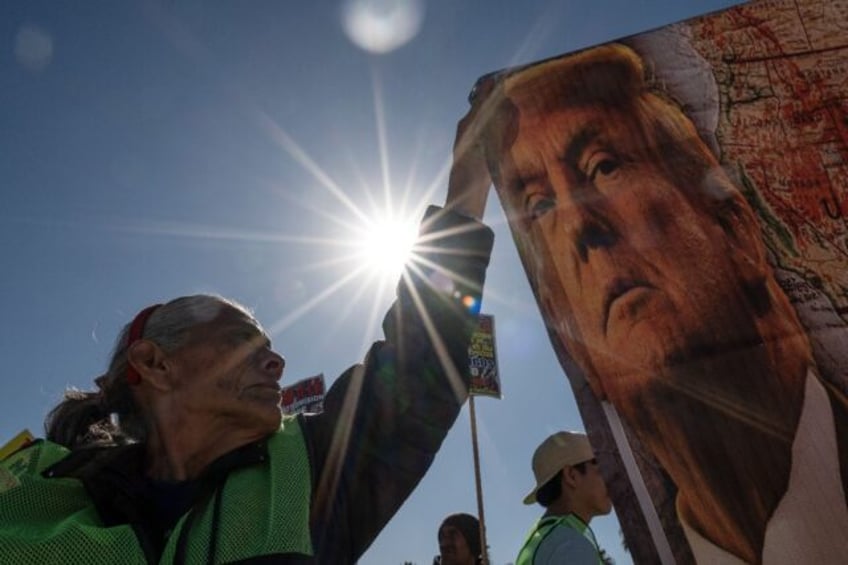 A demonstrator at a Mexico-US border crossing in Tijuana holds a banner with the image of