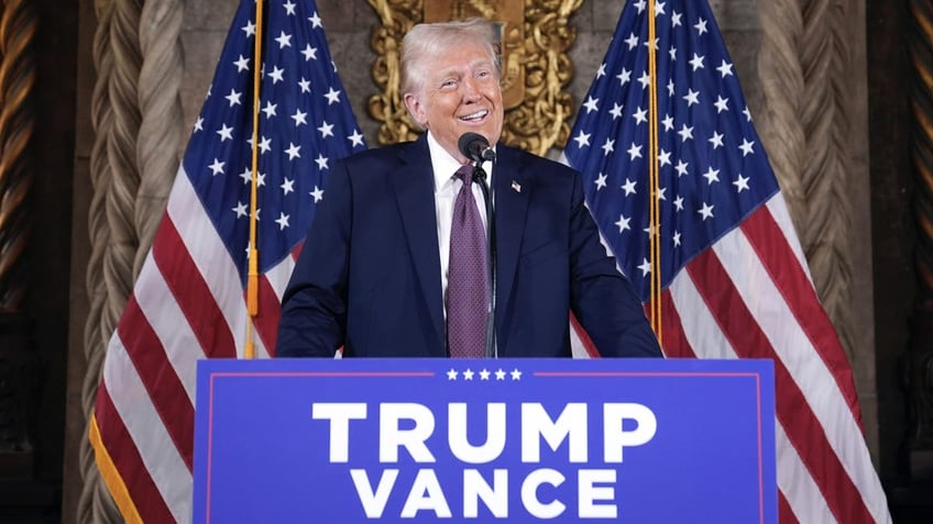 Trump at Trump/Vance lectern, US flag behind him