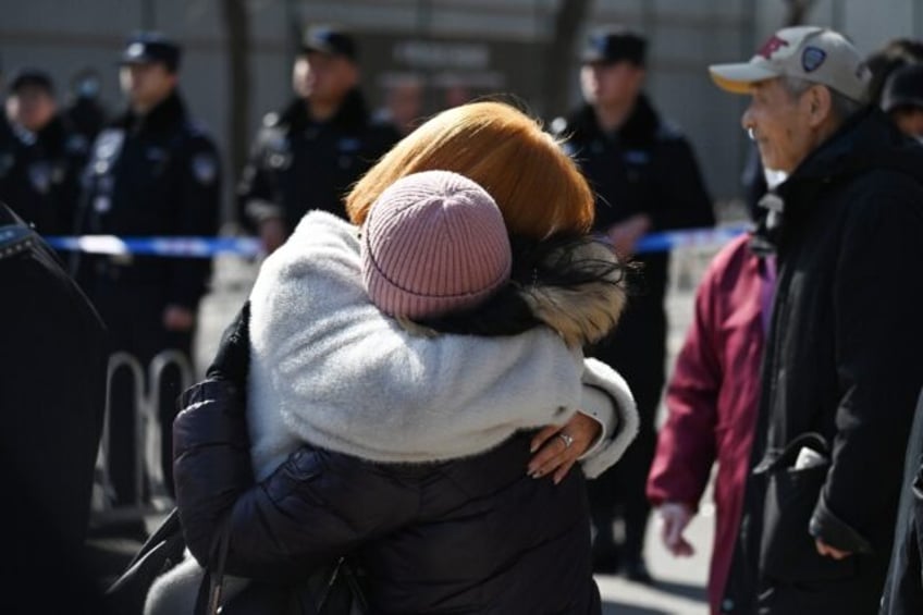 Relatives of passengers on board the missing Malaysian Airlines flight MH370 embrace durin