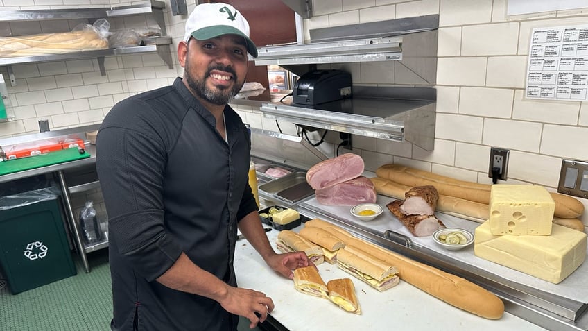 Versailles chef Jose Bido poses with the Cuban sandwich he prepared in the kitchen of the Miami restaurant, Sept. 26, 2024, in Miami.