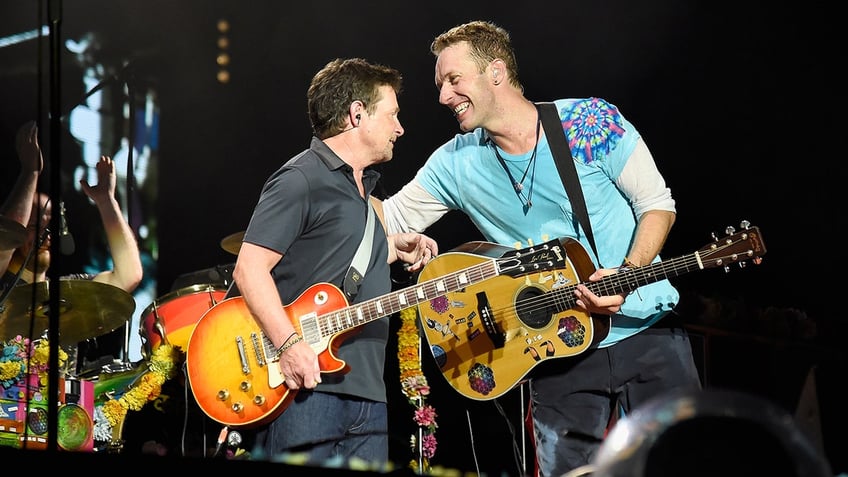 Michael J. Fox and Chris Martin on stage with guitars