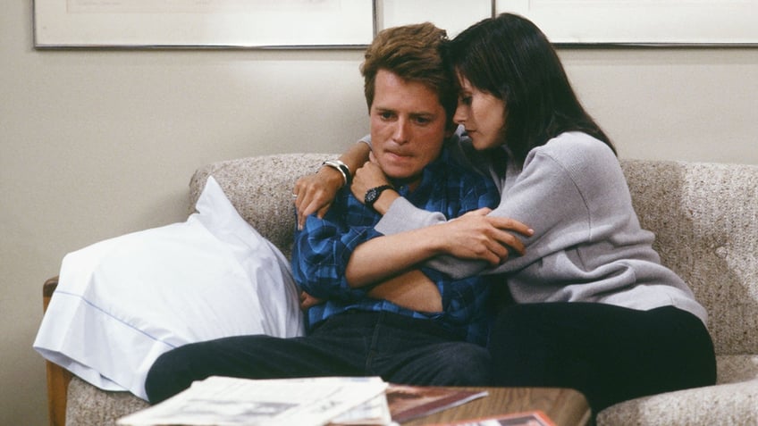 Michael J. Fox as Alex P. Keaton is held on the couchy by Courteney Cox as Lauren Miller on an episode of "Family Ties"