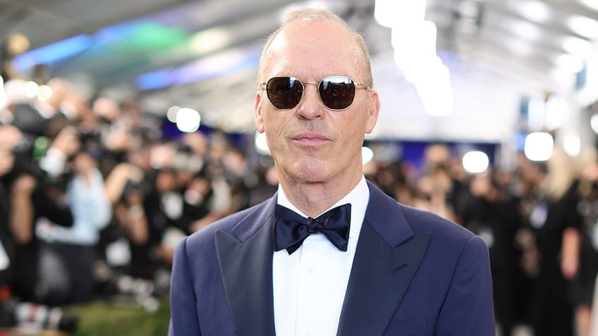 Michael Keaton in a blue tuxedo on the carpet wearing sunglasses