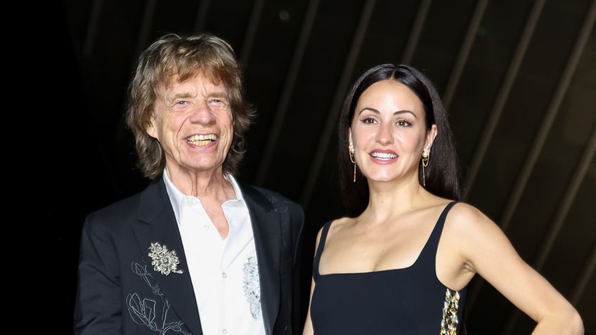 Mick Jagger wears black suit with girlfriend Melanie Hamrock in black dress.