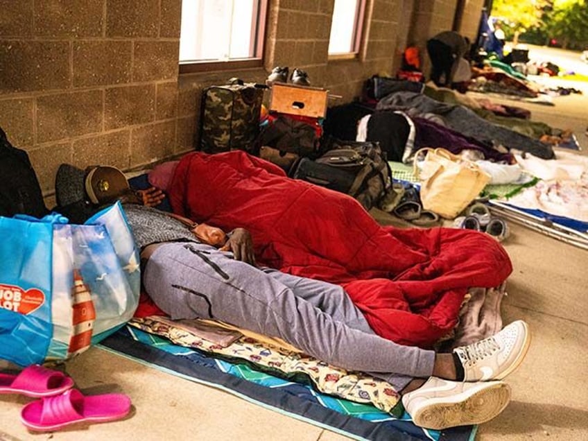 Quincy, MA - August 26: A Haitian migrant lies down outside the Wollaston T stop as people