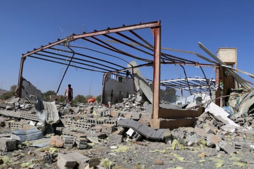 A man inspects the wreckage of a building destroyed in Yemen by a strike on a migrant cent