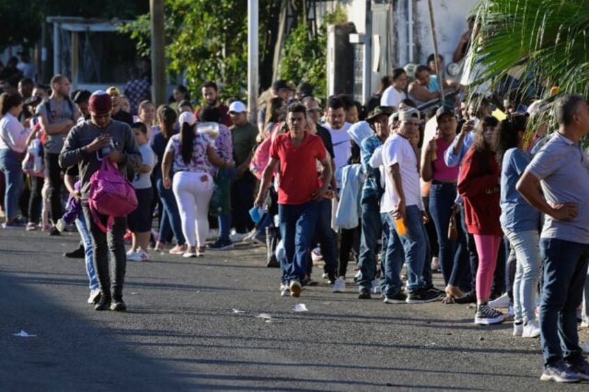 Migrants seeking permits allowing them to travel to the US border wait outside an immigrat