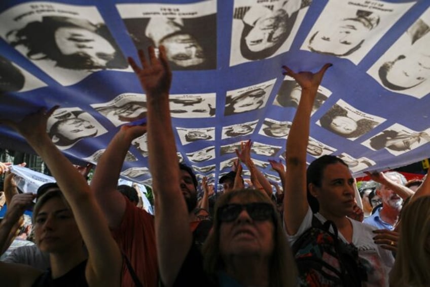 Hundreds of protesting Argentines hold a large banner with portraits of people who disappe