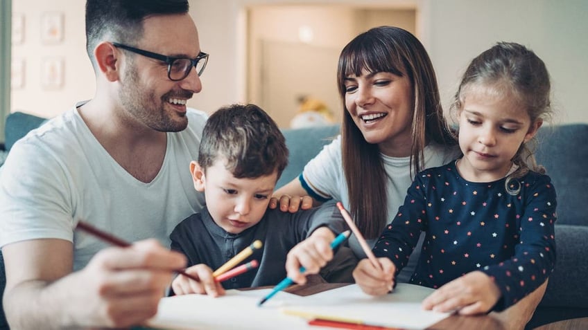 Two parents and a little boy drawing and writing together