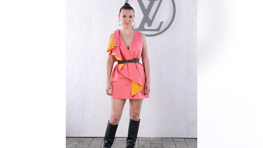 Millie Bobby Brown at the Louis Vuitton show in a pink dress with yellow reverse trim