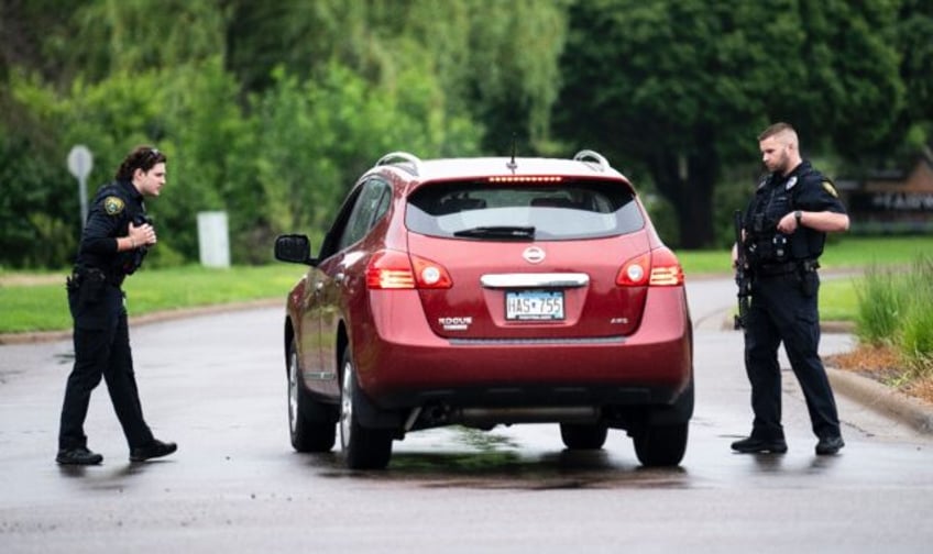 Police officers check a vehicle entering a neighborhood in Brooklyn Park, Minnesota after