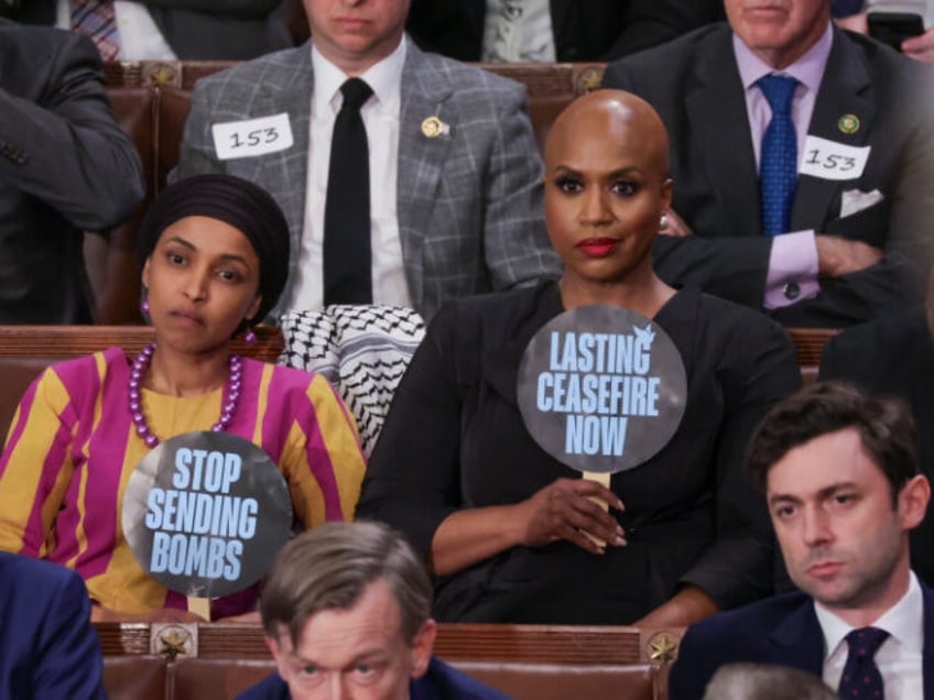 U.S. Rep. Ilhan Omar (D-MN) (L) and Rep. Ayanna Pressley (D-MA) hold up signs as President