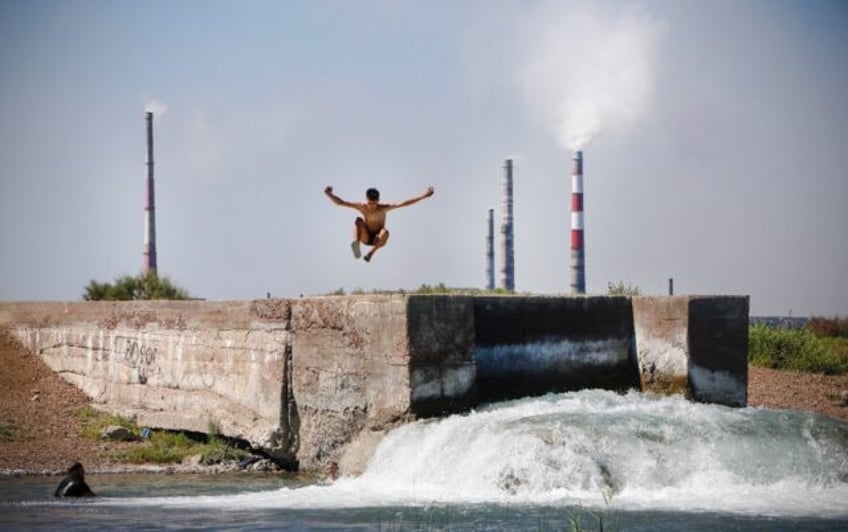 A teenager jumps into the water near the huge Kazakhmys copper plant on the shores of Lake