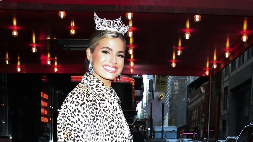 Abbie Stockard smiling and wearing a leopard coat with a crown.