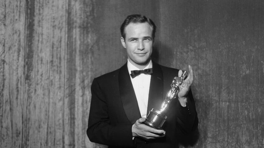 Best actor winner Marlon Brando poses backstage at the 27th Academy Awards holding an Oscar