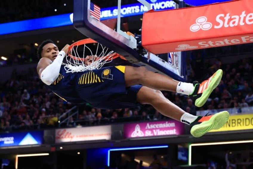 Bennedict Mathurin of the Indiana Pacers hangs on the rim after a dunk in the Pacers' NBA