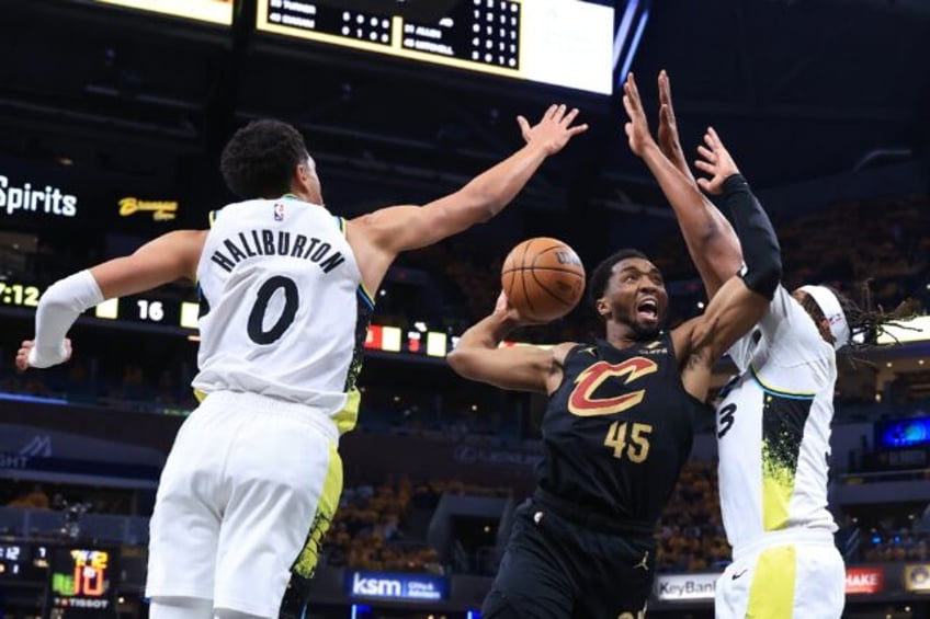 Donovan Mitchell of the Cleveland Cavaliers takes a shot against Tyrese Haliburton and Myl