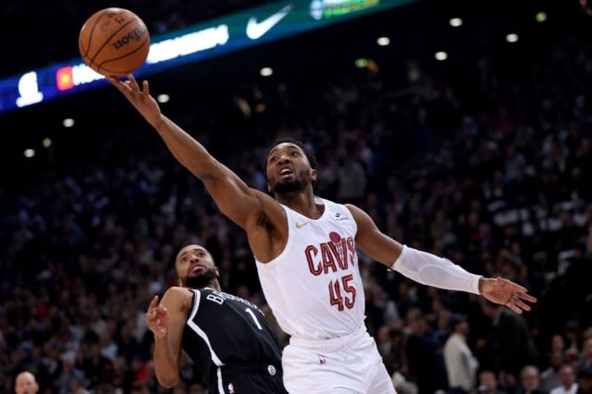 Cleveland guard Donovan Mitchell, right, leaps and scores in front of Brooklyn's Mikal Bridges during the Cavaliers' NBA regular-season triumph in Paris