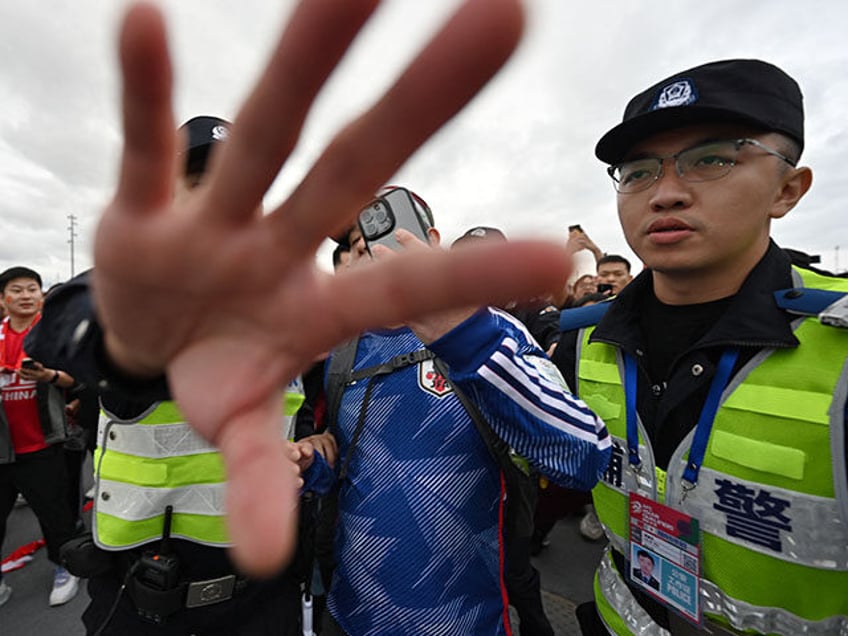 Police block photographers as they provide security escort for a fan (C, obscured), seen w