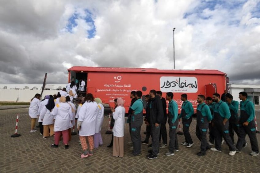 Factory workers line up to watch a film at CinemaTdour's mobile theatre, in Tunisia's town