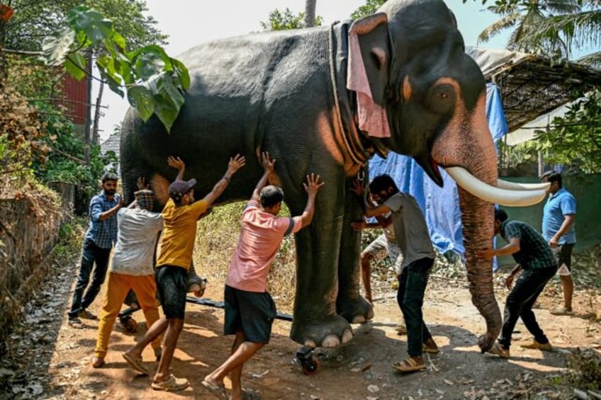 Workers push a finished model of a robotic elephant outside a workshop in Thrissur, in Ind