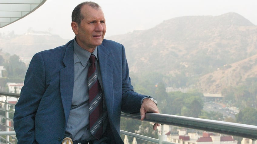 Ed O'Neill in a blue suit on the set of "Dragnet" where he plays a detective
