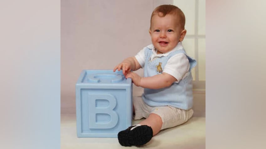 Bryce Balfour wearing light blue overalls and playing with a large block